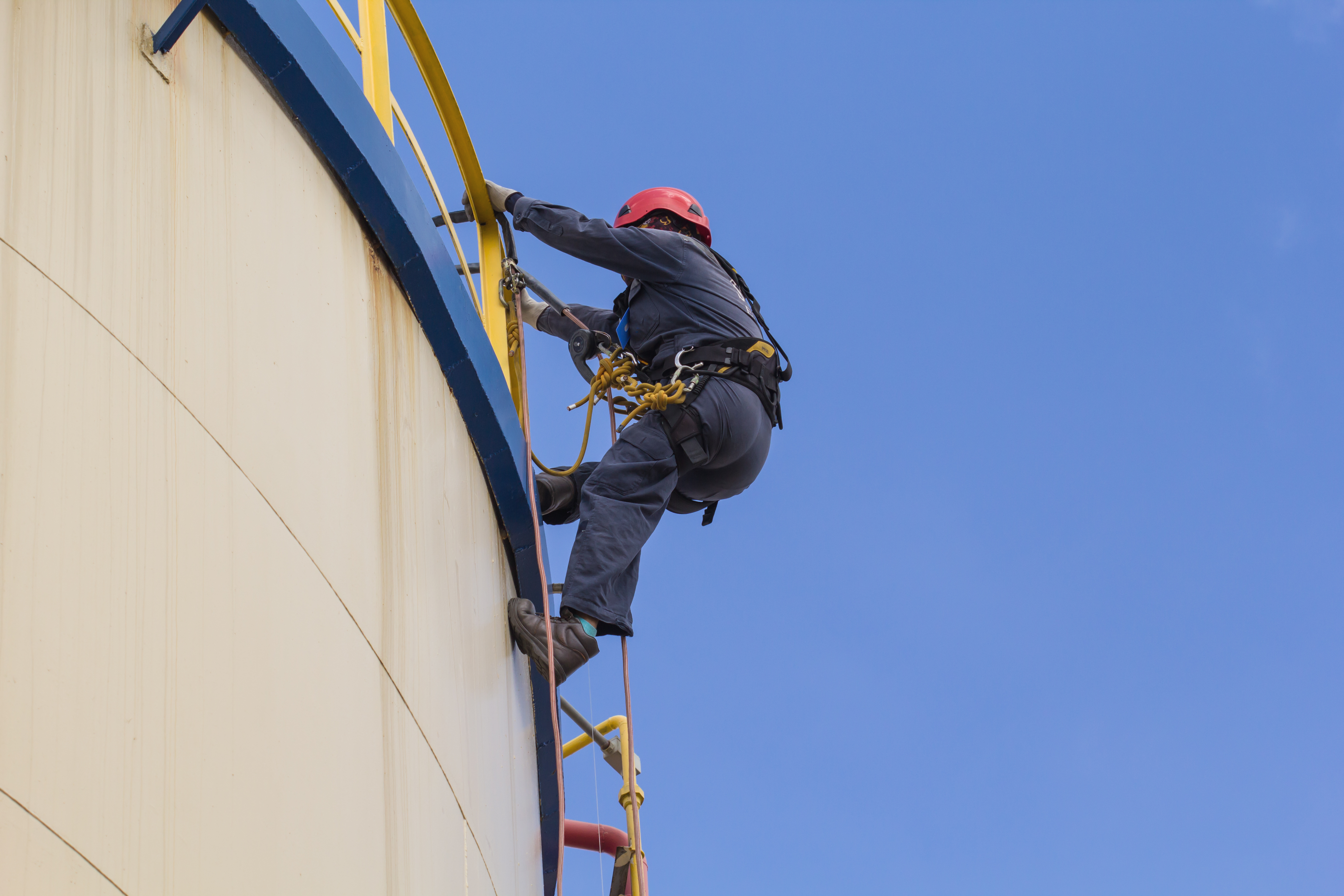 worker descending on ladder from top of tank